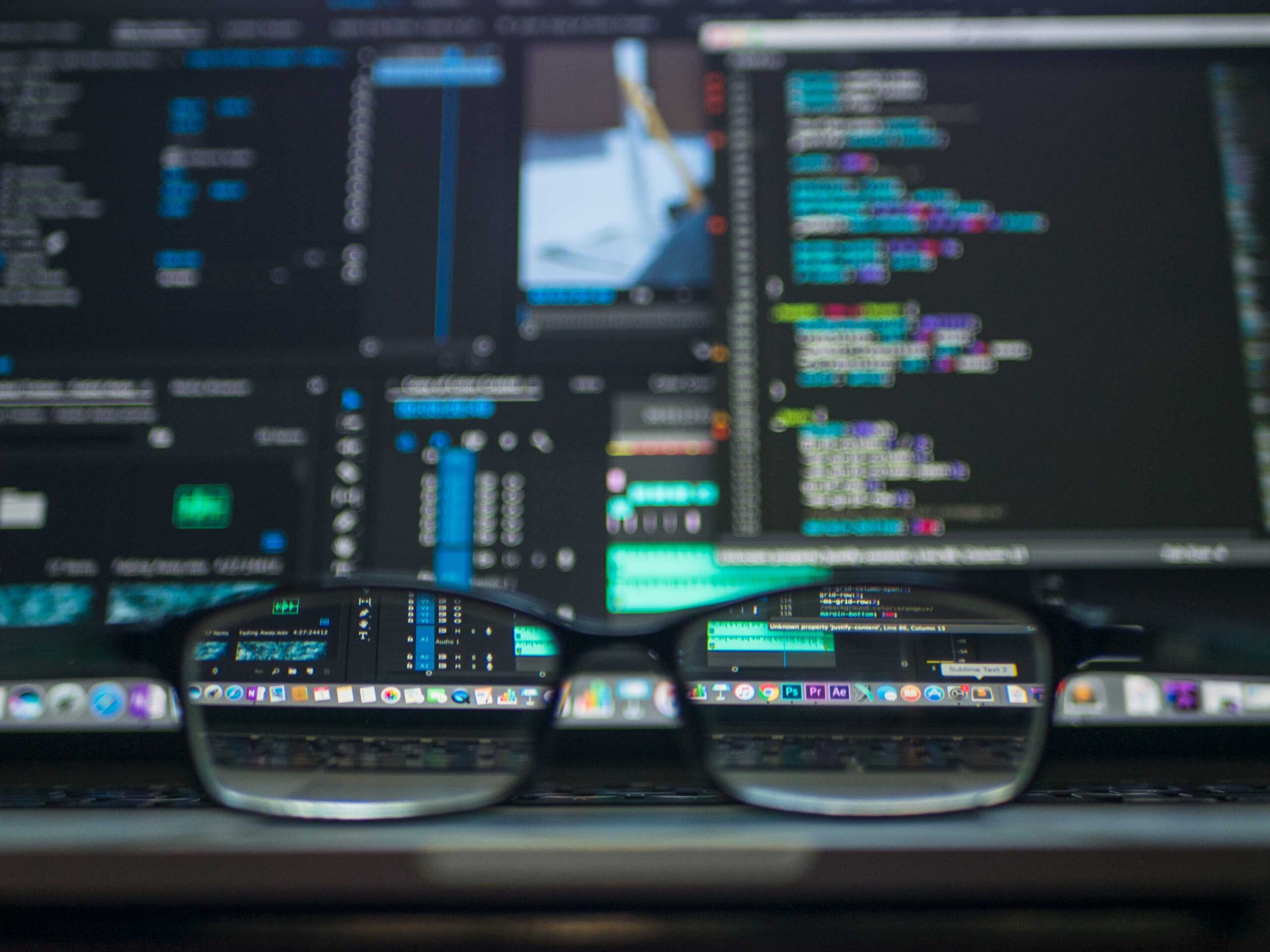 glasses in front of a computer with code for the back end of a website that is checking for security and safety.