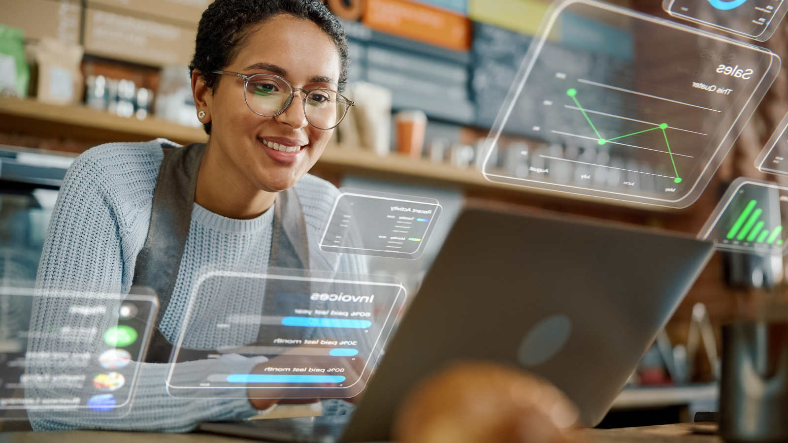 Smiling business owner analyzing sales and performance data on a laptop, using digital tools to track business growth.